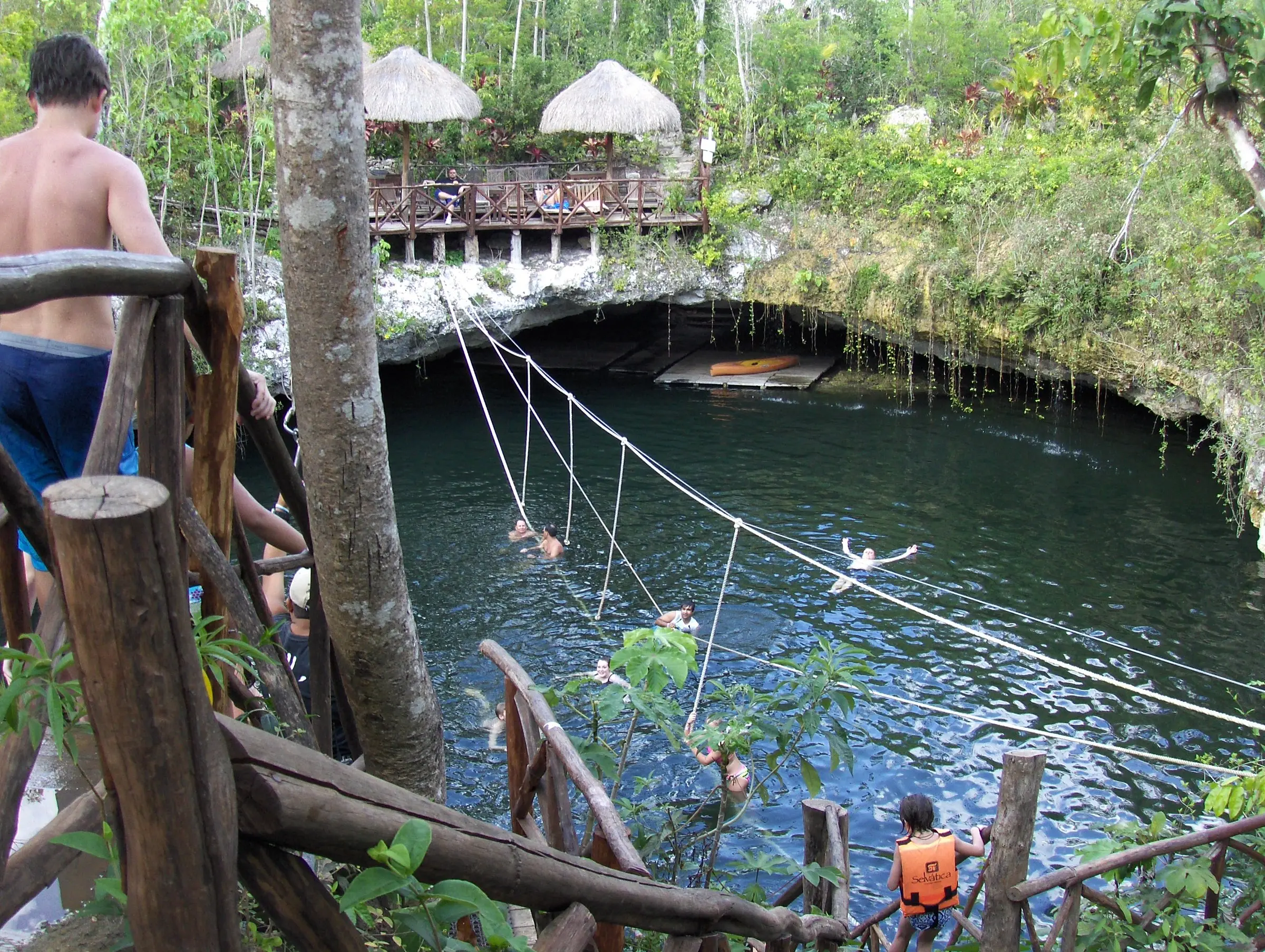 Nada en un cenote de aguas cristalinas.